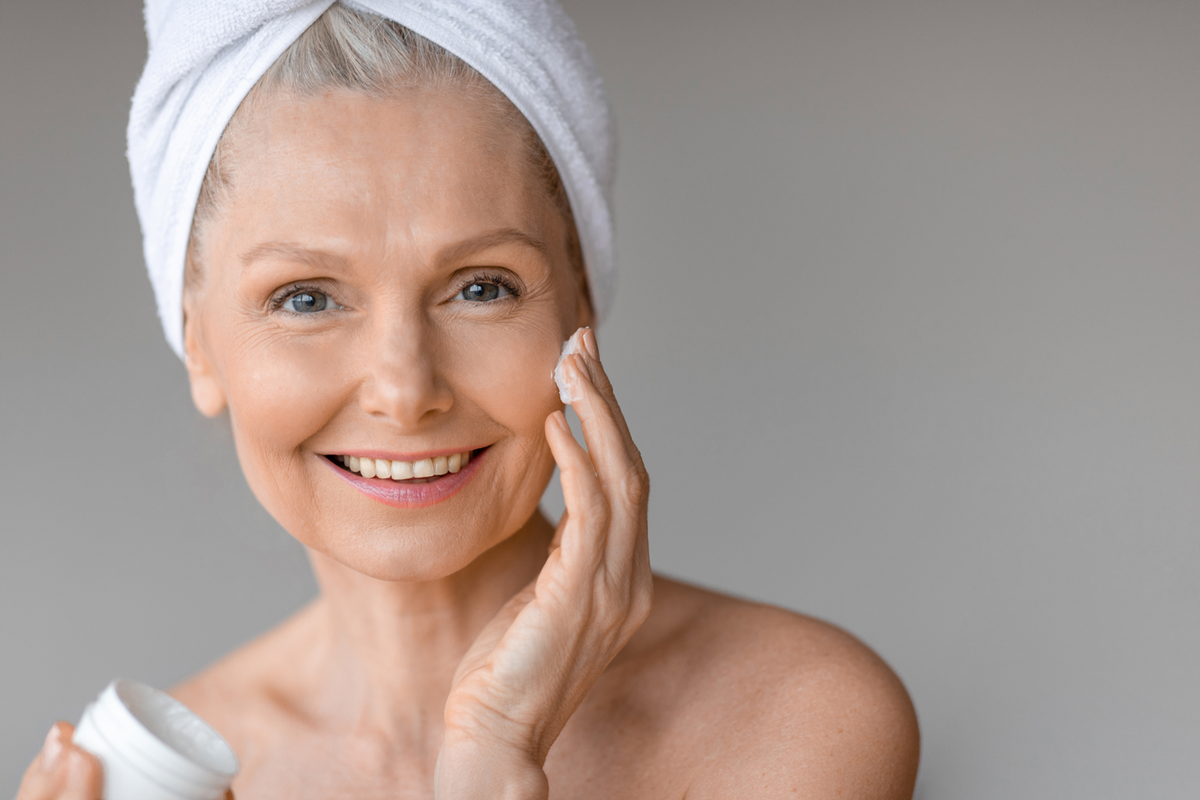 Frau mit gepflegter Haut trägt eine Gesichtscreme auf und unterstützt ihre tägliche Anti-Aging-Hautpflegeroutine.