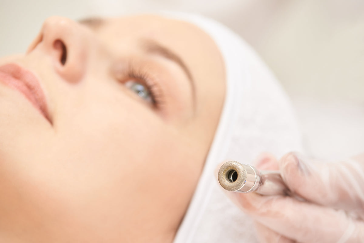 Kosmetikerin führt eine professionelle Mikrodermabrasion im Gesicht einer entspannten Kundin durch.